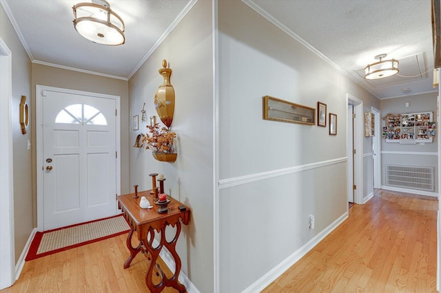 foyer featuring crown molding, a textured ceiling, and light wood-type flooring