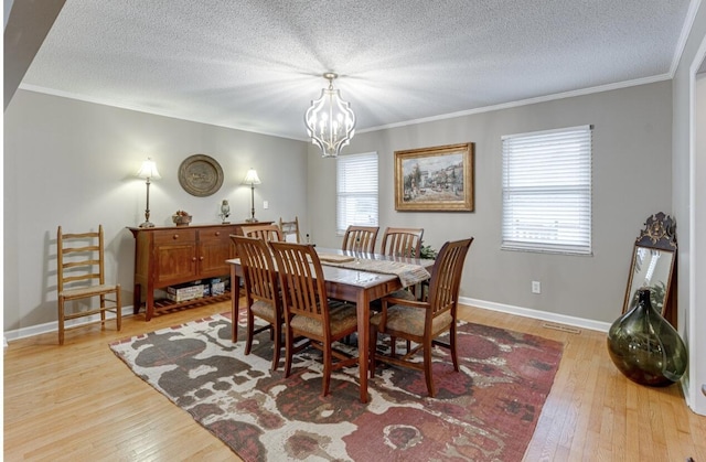 dining space with ornamental molding, an inviting chandelier, a textured ceiling, and light hardwood / wood-style floors