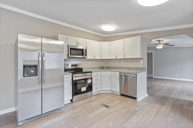 kitchen featuring stainless steel appliances, white cabinetry, backsplash, and ceiling fan