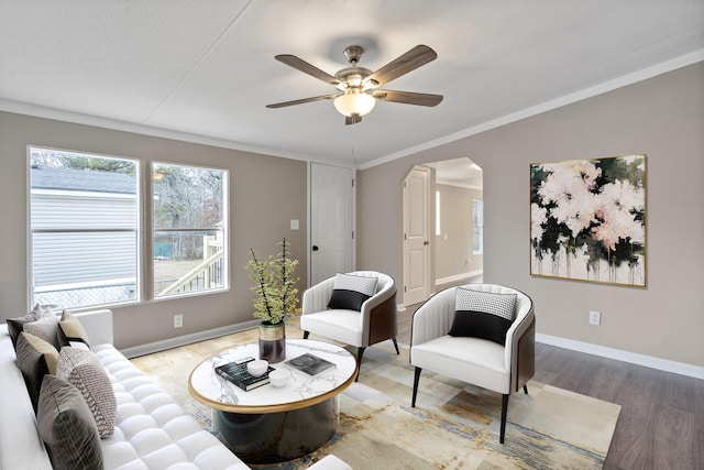 living area featuring hardwood / wood-style flooring, crown molding, and ceiling fan