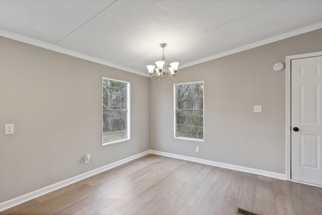 spare room featuring ornamental molding, wood-type flooring, and a chandelier