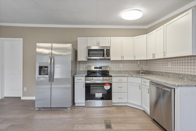 kitchen with sink, light stone counters, appliances with stainless steel finishes, decorative backsplash, and white cabinets