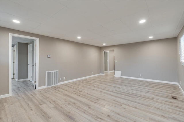 spare room with a paneled ceiling and light wood-type flooring