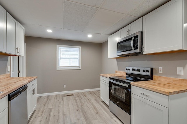 kitchen featuring stainless steel appliances, white cabinets, and wood counters