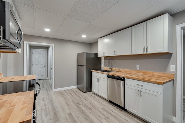 kitchen featuring appliances with stainless steel finishes, butcher block counters, and white cabinets