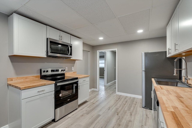 kitchen with white cabinetry, appliances with stainless steel finishes, butcher block counters, and light wood-type flooring