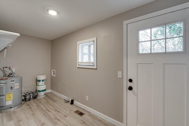 washroom featuring washer hookup, water heater, and light hardwood / wood-style flooring