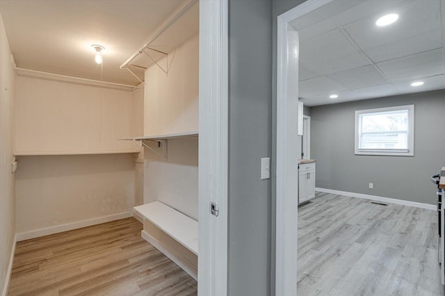 spacious closet featuring a drop ceiling and light wood-type flooring