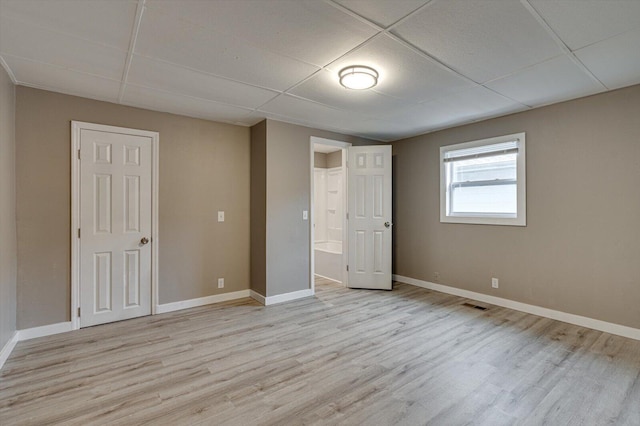 unfurnished bedroom with light hardwood / wood-style flooring and a paneled ceiling