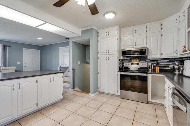 kitchen with light tile patterned floors, stainless steel appliances, kitchen peninsula, and white cabinets