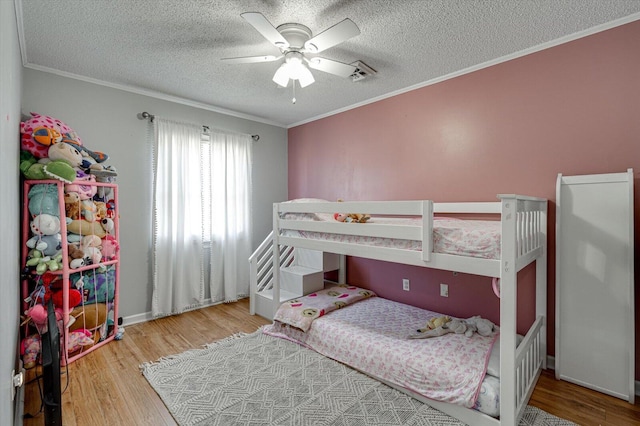 bedroom featuring ornamental molding, light hardwood / wood-style flooring, and a textured ceiling