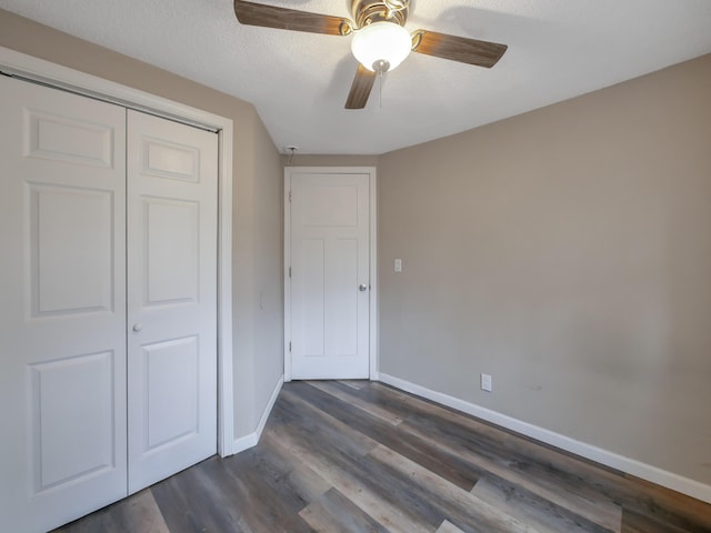 unfurnished bedroom featuring ceiling fan, dark hardwood / wood-style flooring, a closet, and a textured ceiling