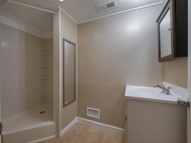 bathroom with tile patterned flooring, vanity, a shower, and a textured ceiling