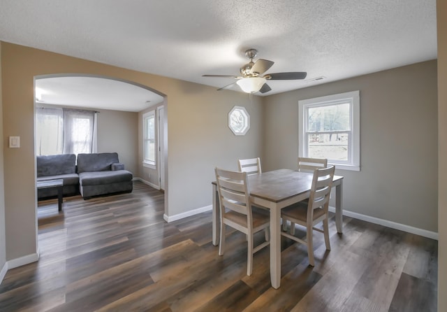 dining space featuring ceiling fan, dark wood-type flooring, and a textured ceiling