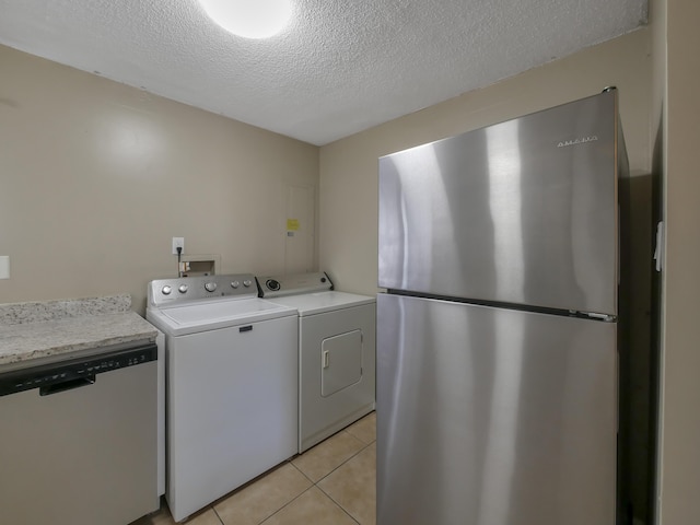 laundry room with washer / clothes dryer, light tile patterned floors, and a textured ceiling