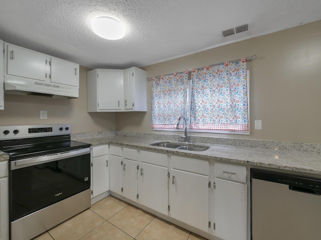 kitchen featuring sink, light tile patterned floors, appliances with stainless steel finishes, white cabinetry, and a textured ceiling