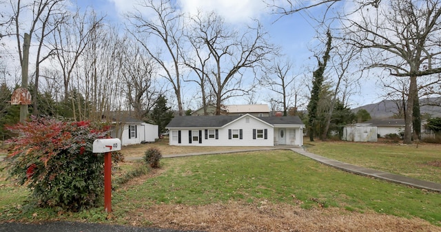 ranch-style house featuring a front lawn and a storage unit