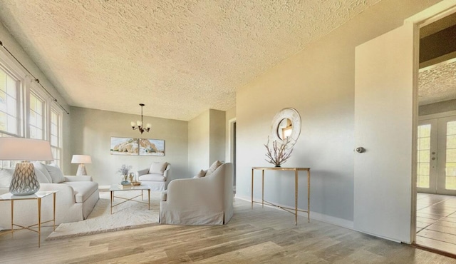 living area with hardwood / wood-style floors, a notable chandelier, french doors, and a textured ceiling