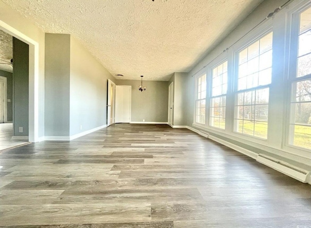 unfurnished room featuring wood-type flooring, a baseboard radiator, a chandelier, and a textured ceiling