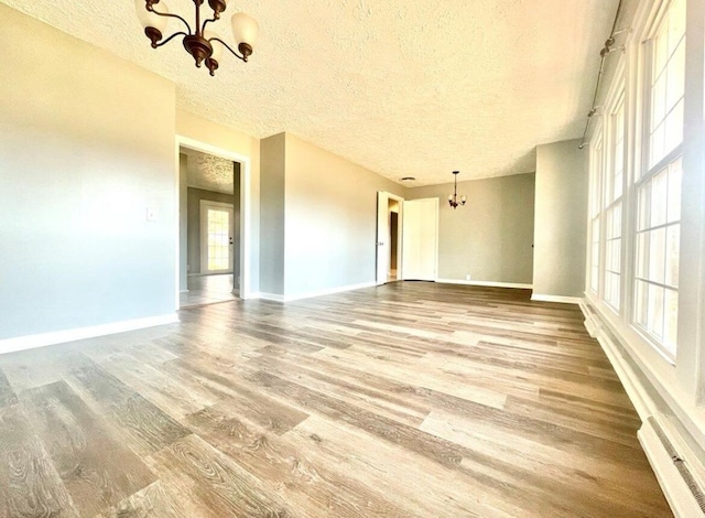 unfurnished room with wood-type flooring, a textured ceiling, and an inviting chandelier