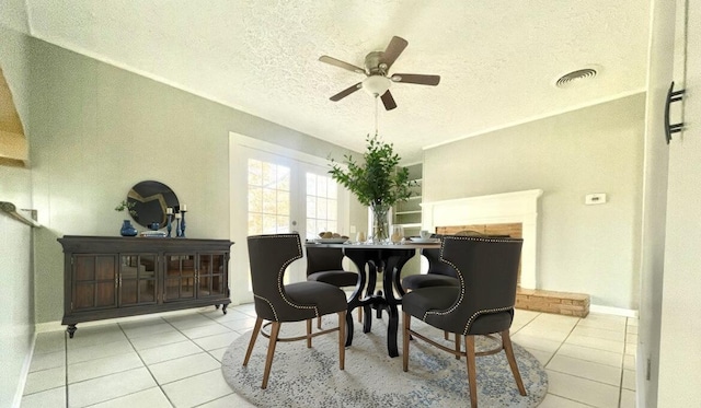 dining room featuring light tile patterned flooring, ceiling fan, a textured ceiling, and a fireplace