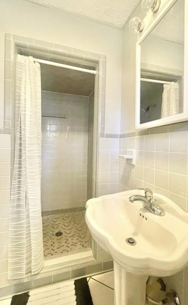 bathroom with tile walls, sink, curtained shower, and tile patterned flooring