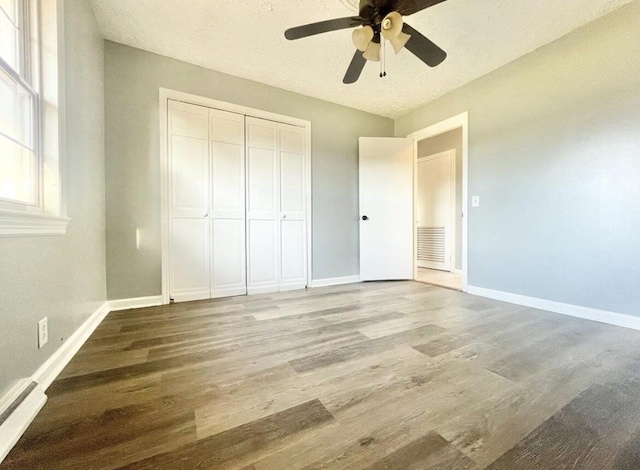 unfurnished bedroom featuring ceiling fan, a closet, light hardwood / wood-style flooring, and a textured ceiling