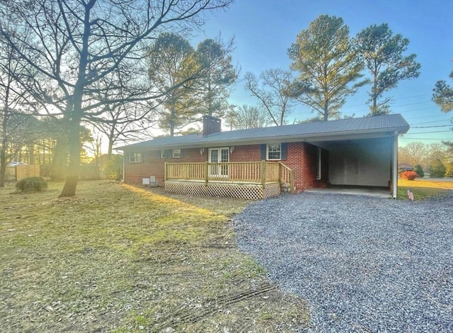 view of front of home with a wooden deck, a front yard, and a carport