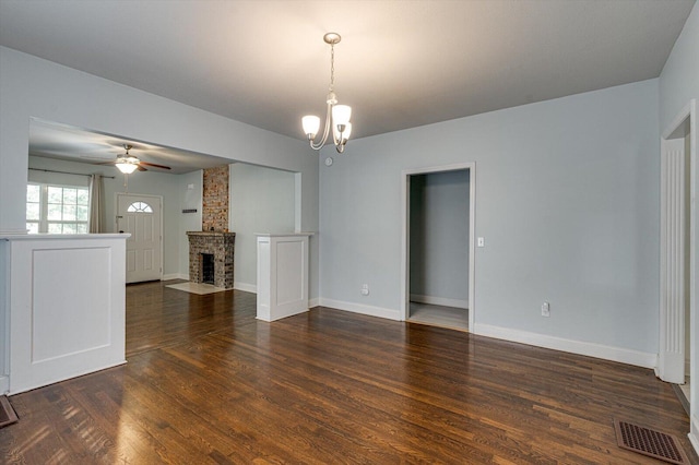 unfurnished living room featuring dark hardwood / wood-style flooring, a brick fireplace, and ceiling fan with notable chandelier