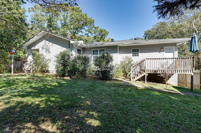 rear view of house with a wooden deck and a lawn