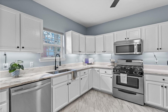 kitchen with white cabinetry, sink, light stone counters, ceiling fan, and stainless steel appliances