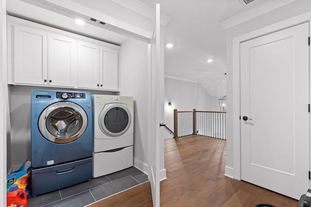 laundry area featuring dark wood-type flooring, washer and clothes dryer, and cabinets