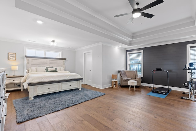 bedroom with dark wood-type flooring, ornamental molding, and a tray ceiling