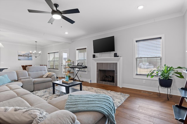 living room featuring hardwood / wood-style floors, ceiling fan with notable chandelier, a fireplace, and ornamental molding