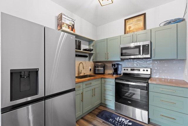 kitchen with stainless steel appliances, butcher block counters, sink, and backsplash