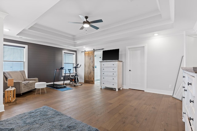 living area featuring a raised ceiling, hardwood / wood-style flooring, and ceiling fan