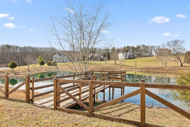 view of dock with a water view and a yard