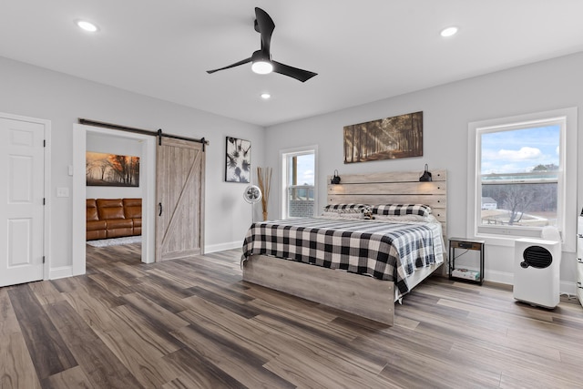 bedroom with a barn door, hardwood / wood-style floors, and ceiling fan