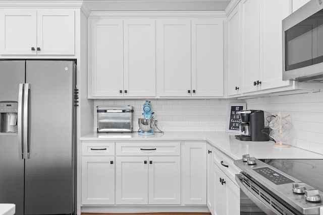 kitchen featuring decorative backsplash, white cabinets, and appliances with stainless steel finishes