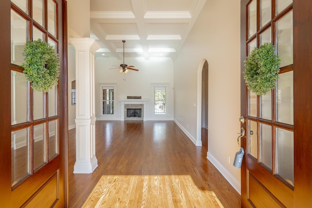 unfurnished living room featuring decorative columns, a premium fireplace, coffered ceiling, and light wood-type flooring