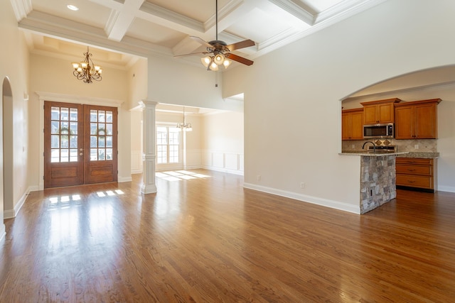 unfurnished living room with french doors, ornate columns, crown molding, dark hardwood / wood-style floors, and beam ceiling