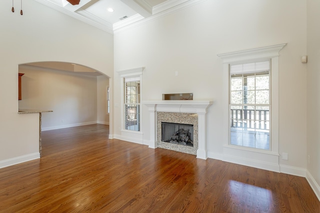 unfurnished living room with dark hardwood / wood-style floors, a high ceiling, ornamental molding, coffered ceiling, and a high end fireplace