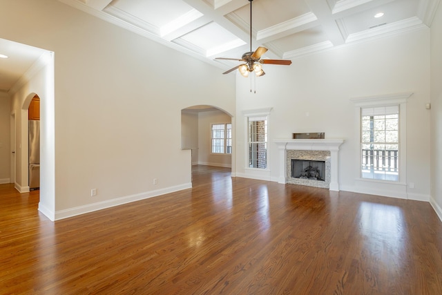 unfurnished living room with a premium fireplace, a towering ceiling, a wealth of natural light, and dark hardwood / wood-style flooring