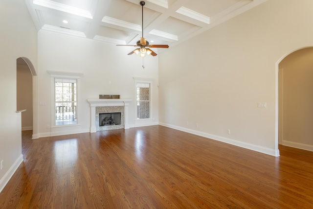 unfurnished living room with coffered ceiling, a towering ceiling, a premium fireplace, and dark hardwood / wood-style flooring