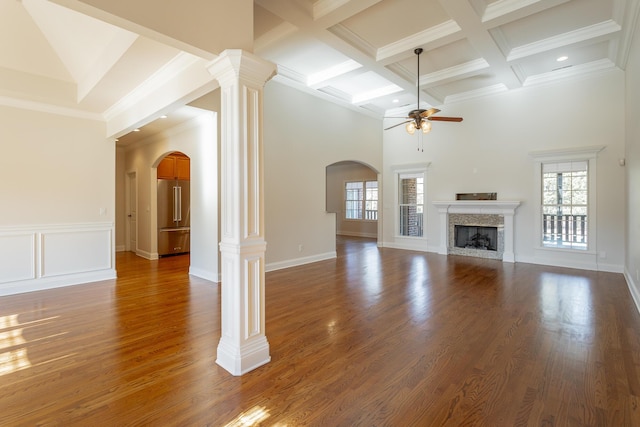 unfurnished living room featuring dark hardwood / wood-style flooring, decorative columns, a premium fireplace, and ceiling fan