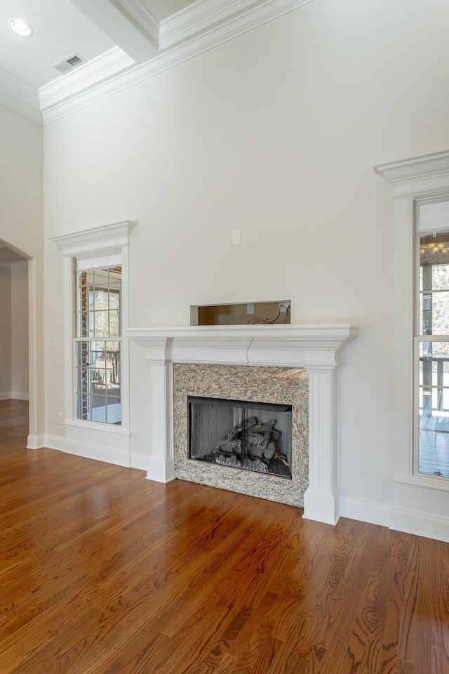 unfurnished living room featuring a premium fireplace, wood-type flooring, and ornamental molding