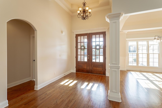 foyer with decorative columns, wood-type flooring, an inviting chandelier, and french doors