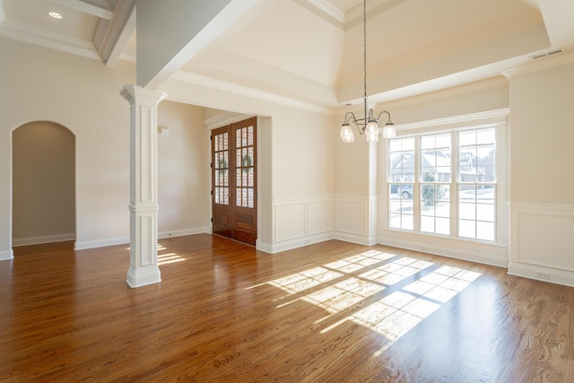 empty room featuring ornate columns, ornamental molding, plenty of natural light, and hardwood / wood-style flooring