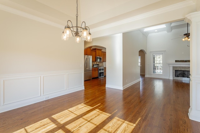 unfurnished living room with beamed ceiling, ornamental molding, dark hardwood / wood-style flooring, and ceiling fan with notable chandelier