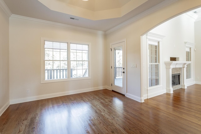 entryway with dark wood-type flooring, ornamental molding, a fireplace, and a raised ceiling